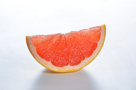 Closeup of a slice of pink grapefruit on a white backgroundの写真素材