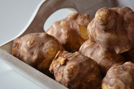 Closeup view of raw Jerusalem artichokes in a wooden boxの写真素材