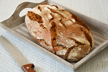 Closeup of a whole country bread on a wooden box with knife