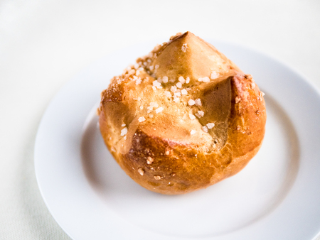 Horizontal view from above of a single  brioche, French  bun, on a white plate and backgroundの写真素材