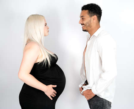 Profile view of a stylish and happy multi-ethnic couple expecting a baby