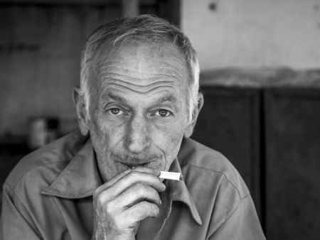 Man that sells tobacco on a local market in Batumi makes a cigarette for a client  Smoking is...