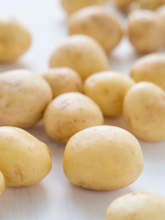 New raw potatoes on a white wooden table の写真素材