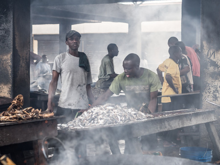 Local people frying fish on the fish market in the port in Dar es Salaam, Tanzania, East Africa, on a weekend. Horizontal orientation.のeditorial素材