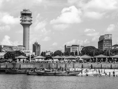 Black and white photo of the waterfront of Dar es Salaam, Tanzania in East Africa, with maritime control tower and the fish market. Local people on boats.のeditorial素材