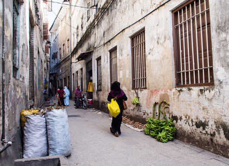 Local people walking on one of the narrow streets in old part of Stone Town, Zanzibar in East Africa. Horizontal orientation, wide angle.のeditorial素材