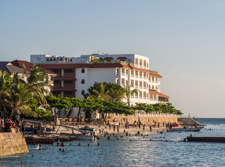 Local people walking on the seafront in Stone Town, Zanzibar, Tanzania, East Africa and jumping to the water on the sunny evening. Horizontal orientation.のeditorial素材