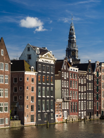 Traditional houses over Damrak canal in the old town of Amsterdam, Netherlands, on a summer day. Tower of the Oude church in the background.のeditorial素材