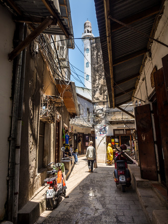 One of the narrow streets in the old part of Stone Town, Zanzibar in East Africa. Vertical orientation, wide angle. Mosque's minaret in the background.のeditorial素材