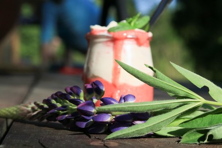Strawberry dessert on a wooden plank with a single wild flowerの写真素材