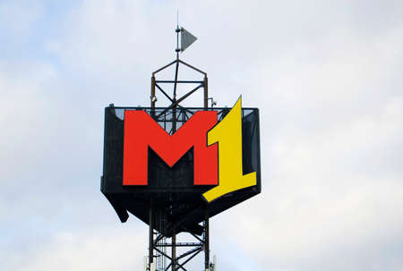 Poznan, Poland - February 5th 2022: M1 shopping center signboard on blue sky and clods background.