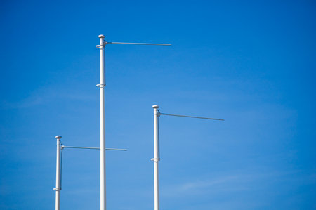 Triple empty flagpole against blue sky.の写真素材