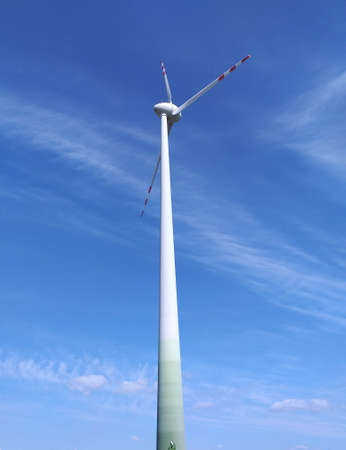 Windmill for electric power production against blue sky.