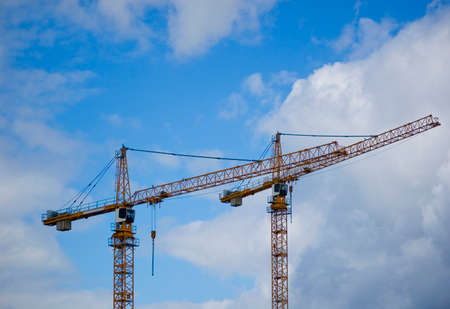 Large construction site crane working on a building complex with cloudy sky.の写真素材