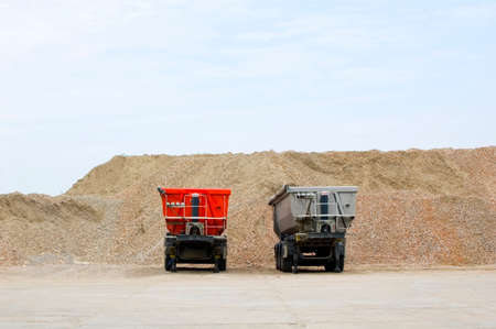 Piles of crashed rock and dumpers at gravel pit.の写真素材