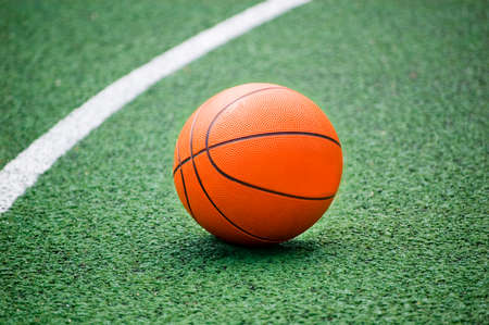 Orange basket ball lying on green playground.の写真素材