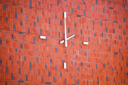 Modern clock on the brick building wall.の写真素材