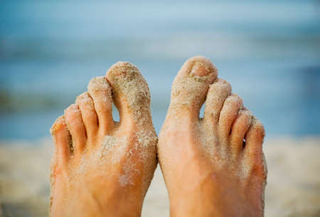 Bare feet on the beach cover with sand.の写真素材