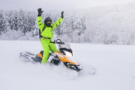 Athlete on a snowmobile moving in the winter forest
