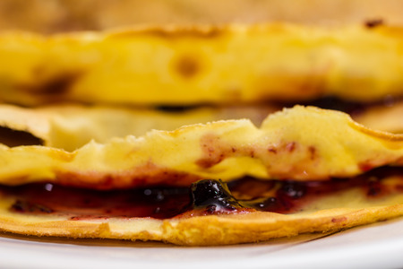 Fresh pancakes on plate. Close up of a homemade crepe with jam filling, shallow depth of field.