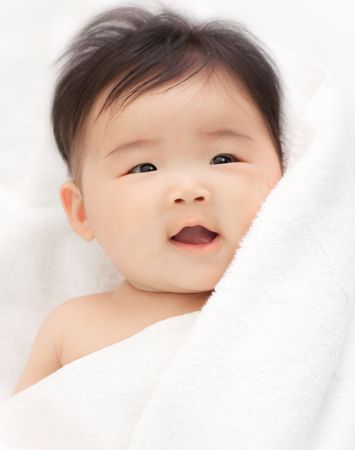 A smiling babywith her hair just dried with a towel.の写真素材