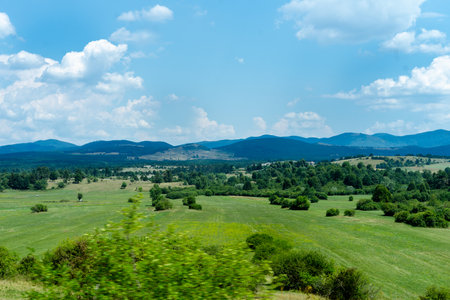 Beautiful summer landscape with green hills, blue sky and white cloudsの写真素材