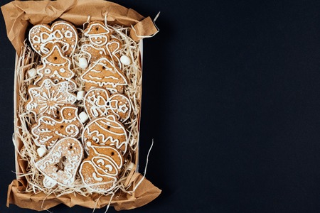 Flat lay of Christmas gingerbread cookies with glaze in the present box in rustic style isolated on black background. Star, heart, bell, santa shape figures. Top viewの写真素材