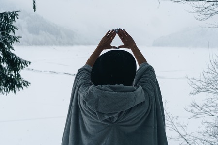 Woman making triangle gesture symbol with her hands in front of beautiful mountains outdoors in the...