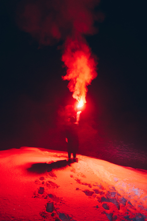 Rear view of woman standing on the top of the mountain with red fire torch with the smoke.の写真素材