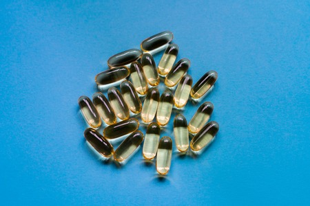 Capsules of fish fat oil, omega 3, vitamin e on the blue background. Healthy food diet