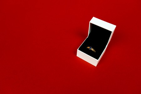 Luxury golden ring with blue gemstone in the white box isolated on red background. Valentines Day. Top view. Giftの写真素材