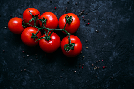 Top view of beautiful fresh organic tomatoes on branch isolated on black sony background. Healthy ripe vegetablesの写真素材