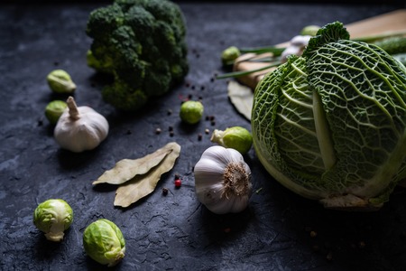 Close up fresh ripe green vegetables on black rustic table. Organic cabbage, brussels sprouts, broccoli, garlic. Healthy foodの写真素材