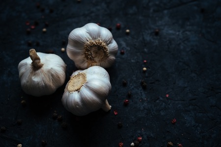 Close up three whole garlic bulbs isolated on black stone table background. Flat lay. Top view. Healthy food concept. Copy spaceの写真素材