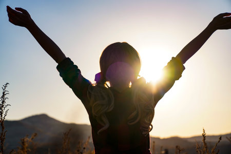 A blonde woman in a plaid shirt stands in a field of tall grass. happy woman outdoors at sunset on...