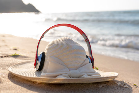 Straw hat with headphones on the beach. Selective focus.の写真素材