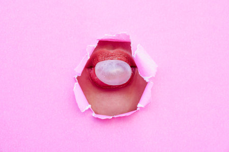 A woman blowing gum in her mouth from torn pink paper. advertising and creative concept. copy space...