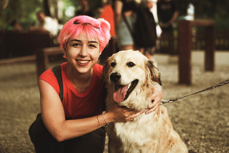 Portrait of a smiling young woman with her dog in the parkの写真素材