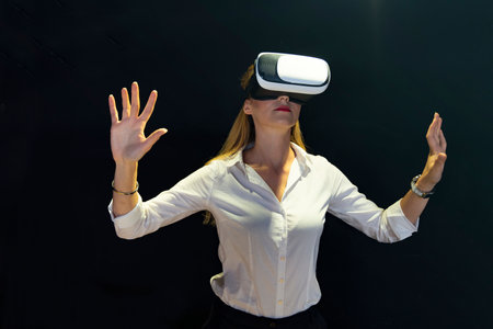 A woman is playing a video game with a virtual reality headset. Business woman wearing virtual reality headsetの写真素材
