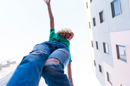 young cheerful woman dancing in the city and wearing headphones