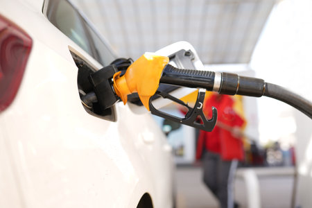 A car is being filled with gas at a gas station. The gas pump is black and silverの写真素材