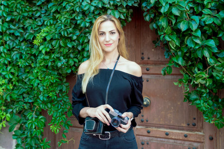 a woman woman takes photos with an old camera in the city