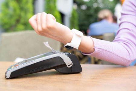 A woman is using a credit card reader to pay for something. paying with smart watch