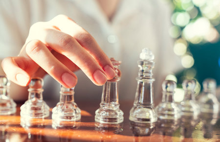 A woman is playing chess and is about to move a piece. strategic decision making and victory concept
