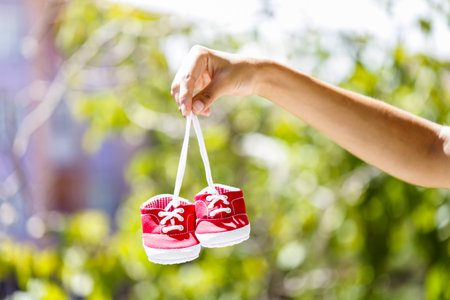 A hand holding red baby shoesの写真素材