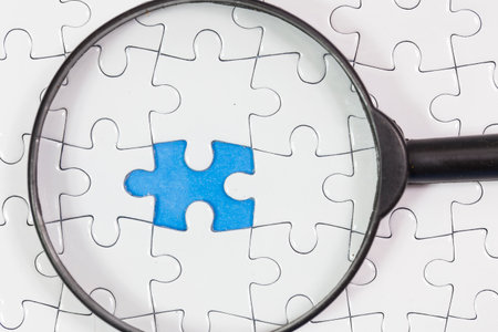 A puzzle with one piece missing and a magnifying glass. business and success concept