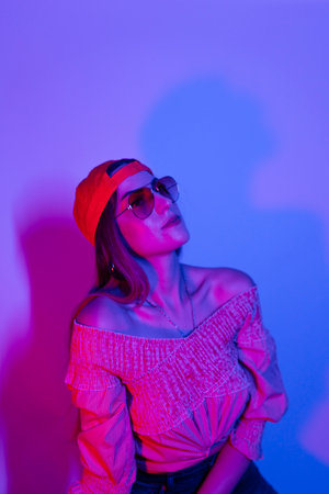 High Fashion model woman in colorful bright neon blue and purple lights posing in studio. Portrait...