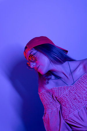 High Fashion model woman in colorful bright neon blue and purple lights posing in studio. Portrait...