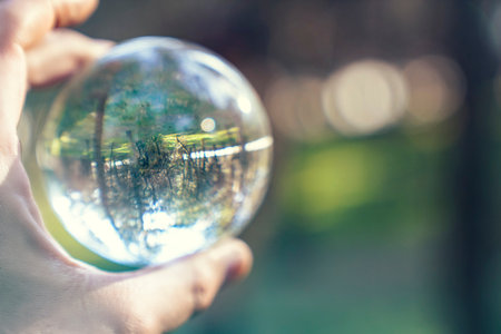 A hand holding a glass ball with a green background