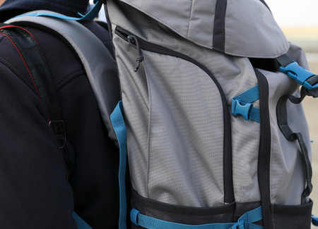 A person wears a backpack with straps in nature